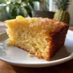 Ein saftiges St&uuml;ck Ananaskuchen mit karamellisierter Ananas-Decke, serviert auf einem wei&szlig;en Teller.