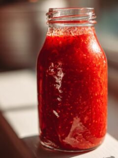 Nahaufnahme einer Glasflasche gef&uuml;llt mit leuchtend roter Erdbeer-Vinaigrette, bereit f&uuml;r Salate.