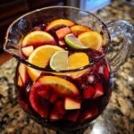 Ein Krug mit erfrischender Star Spangled Sangria, gef&uuml;llt mit Orangen-, Limetten- und Apfelst&uuml;cken sowie Eis.