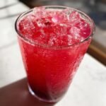 Ein Glas voller erfrischendem Beeren-Slush mit Eisw&uuml;rfeln und Kondenswasser, perfekt f&uuml;r den Sommer.