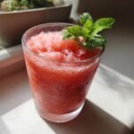 Ein Glas mit einem erfrischenden Wassermelonen-Slushie, garniert mit Minze, perfekt f&uuml;r den Sommer.