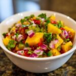 Nahaufnahme einer Sch&uuml;ssel mit einer erfrischenden Fruchtsalsa aus Mango, roter Zwiebel, Jalape&ntilde;o und Koriander.