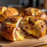 Aufgeschnittene Pretzel Bombs mit ger&auml;uchertem Brisket und schmelzendem Bierk&auml;se, garniert mit K&auml;se und Kr&auml;utern.