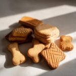 Nahaufnahme eines Haufens hausgemachter Hundeleckerlis in verschiedenen Formen, darunter Knochen und Quadrate.