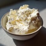 Nahaufnahme von hausgemachtem Frischk&auml;se in einer rustikalen Sch&uuml;ssel, im Sonnenlicht.