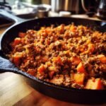 Nahaufnahme einer herzhaften Hackfleisch-S&uuml;&szlig;kartoffel-Pfanne in einer Gusseisenpfanne.