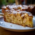 Ein saftiges St&uuml;ck italienischer Apfelkuchen, best&auml;ubt mit Puderzucker, auf einem Teller serviert.