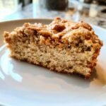 Ein St&uuml;ck Keto Erdnussbutter Cookie Cake auf einem wei&szlig;en Teller, mit sichtbarer Textur und Kruste.