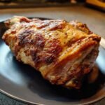 Nahaufnahme eines knusprigen bayerischen Schweinehaxens auf einem dunklen Teller, perfekt gebraten.