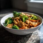 Sch&uuml;ssel mit magischem Eirollgericht: H&auml;hnchenstreifen mit Brokkoli und Karotten in einer gl&auml;nzenden Sauce.