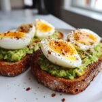 Perfekter Avocado Toast mit 6-Minuten-Eiern, garniert mit Chiliflocken und Pfeffer.