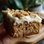 Ein St&uuml;ck saftiger Bananen-Riegel mit cremigem Frischk&auml;se-Frosting und Waln&uuml;ssen.