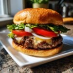 Ein saftiger Burger mit geschmolzenem K&auml;se, Tomaten, Zwiebeln und Salat auf einem Br&ouml;tchen.