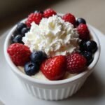 Ein schnelles und einfaches fabelhaftes Dessert mit Beeren und Schlagsahne in einer wei&szlig;en Sch&uuml;ssel.