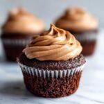Nahaufnahme eines saftigen Schokoladen-Kaffee-Creme-Cupcakes mit cremiger Schokoladen-Kaffee-Glasur.