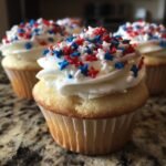 Nahaufnahme von Sternen & Streifen Cupcakes mit wei&szlig;er Glasur und roten, blauen und wei&szlig;en Sternstreuseln f&uuml;r den 4. Juli.