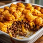 Nahaufnahme einer Auflaufform mit dem Ultimate Cheeseburger Tater Tot Casserole Rezept, geschmolzenem K&auml;se und knusprigen Tater Tots.