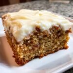 Ein St&uuml;ck unwiderstehlicher Bananenriegel mit cremigem Frischk&auml;se-Frosting auf einem wei&szlig;en Teller.