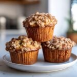 Drei unwiderstehliche Kaffee-Kuchen-Bananenbrot-Muffins mit Streuseln auf einem Teller gestapelt.