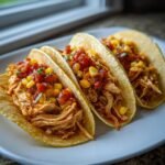 Drei unwiderstehliche Slow Cooker H&auml;hnchen-Tacos gef&uuml;llt mit zartem H&auml;hnchenfleisch, Mais und Salsa.