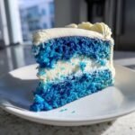 Ein Anschnitt eines unwiderstehlichen blauen Samt Kuchens mit wei&szlig;er Creme und blauen Kuchenschichten.