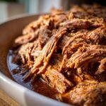 Nahaufnahme von zartem, zerfallenem italienischem Rindfleisch aus dem Crockpot, serviert in einer Sch&uuml;ssel.