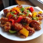 Nahaufnahme eines k&ouml;stlichen S&uuml;&szlig;-Sauer-H&auml;hnchen-Gerichts mit Paprika und Fr&uuml;hlingszwiebeln.