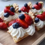 Nahaufnahme von kleinen T&ouml;rtchen mit Sahne, Erdbeeren und Blaubeeren, perfekt f&uuml;r ein 4. Juli Dessert-Brett.