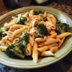 Nahaufnahme einer Sch&uuml;ssel mit cremiger Brokkoli-H&auml;hnchen-Penne, garniert mit frisch gemahlenem Pfeffer.