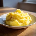 Nahaufnahme von cremigem, gelbem P&uuml;ree, das wahrscheinlich Mashed Turnips ist, auf einem Teller.