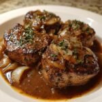 Nahaufnahme von drei saftigen Crock Pot Pork Chops in einer reichhaltigen braunen So&szlig;e mit karamellisierten Zwiebeln.