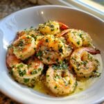 Nahaufnahme von saftigen Easy Garlic Shrimp in einer wei&szlig;en Sch&uuml;ssel, bedeckt mit Petersilie und Knoblauch.