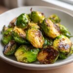 Nahaufnahme von kross gebratenen Easy Smashed Brussel Sprouts in einer hellen Sch&uuml;ssel.