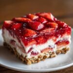 Ein St&uuml;ck Erdbeer Pretzel Jello Salad mit Schichten von Brezelkruste, Frischk&auml;sef&uuml;llung und Erdbeergelee.