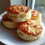 Stapel von vier goldbraun gebackenen Drop Scones auf einem wei&szlig;en Teller.