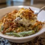 Ein L&ouml;ffel voll cremigen Green Bean Casserole mit gr&uuml;nen Bohnen und knusprigen R&ouml;stzwiebeln.