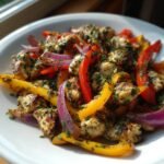 Nahaufnahme von griechischem H&auml;hnchen mit Paprika und Zwiebeln, garniert mit Kr&auml;utern.