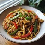 Nahaufnahme von hausgemachtem H&auml;hnchen Lo Mein mit viel H&auml;hnchenfleisch, Paprika und Zuckerschoten.