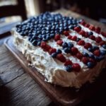 Rechteckiger Kuchen mit wei&szlig;er Glasur, dekoriert mit Blaubeeren und Himbeeren in Form einer amerikanischen Flagge f&uuml;r den 4. Juli.