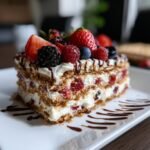 Ein St&uuml;ck No Bake Summer Berry Lasagna mit frischen Beeren und Schokoladensauce.