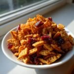 Nahaufnahme von Orange Cranberry Chex Mix mit getrockneten Cranberrys in einer wei&szlig;en Schale.