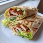Ein aufgeschnittener H&auml;hnchen Caesar Wrap, gef&uuml;llt mit gegrilltem H&auml;hnchen, Salat und cremiger Sauce.