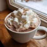 Eine Tasse Spiked Crockpot Hot Chocolate, bedeckt mit Schlagsahne und Marshmallows.