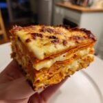 Nahaufnahme eines dicken St&uuml;cks S&uuml;&szlig;kartoffelgratin mit geschichteten S&uuml;&szlig;kartoffeln und geschmolzenem K&auml;se.