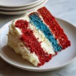 Ein St&uuml;ck klassischer Throwback Fourth Of July Cake mit roten, wei&szlig;en und blauen Schichten und wei&szlig;er Glasur.