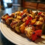 Nahaufnahme von unwiderstehlichen H&auml;hnchenspie&szlig;en mit gegrilltem Gem&uuml;se auf einem Teller.