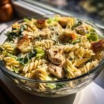 Eine Sch&uuml;ssel mit Wholesome Caesar Pasta Salad Delight, garniert mit gegrilltem H&auml;hnchen, Croutons und Parmesan.