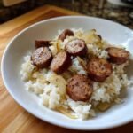 Nahaufnahme von gebratener Wurst und Zwiebeln auf wei&szlig;em Reis, das Gericht hei&szlig;t Wurst und Reis.