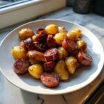 Gebratene Wurstscheiben und goldbraune Kartoffeln auf einem wei&szlig;en Teller: Air Fryer Wurst und Kartoffeln.