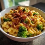 Nahaufnahme von cremigem Broccoli Bacon Macaroni And Cheese mit knusprigem Speck-Topping in einer wei&szlig;en Sch&uuml;ssel.